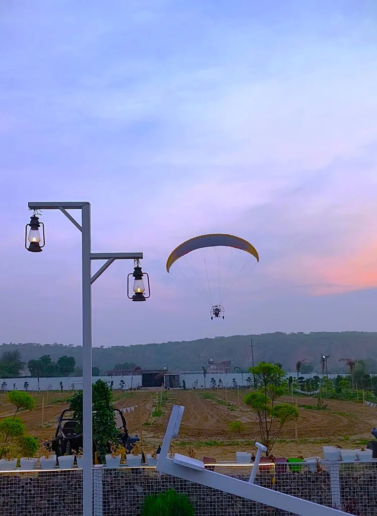 Paramotor flying in sunset skies over fields