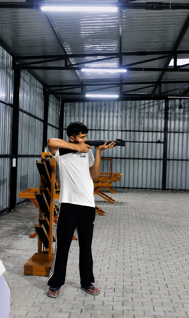Person Aiming Rifle in Indoor Shooting Range